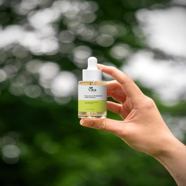 Hand holding the Bioactive Prebiotics Jelly Serum bottle outdoors